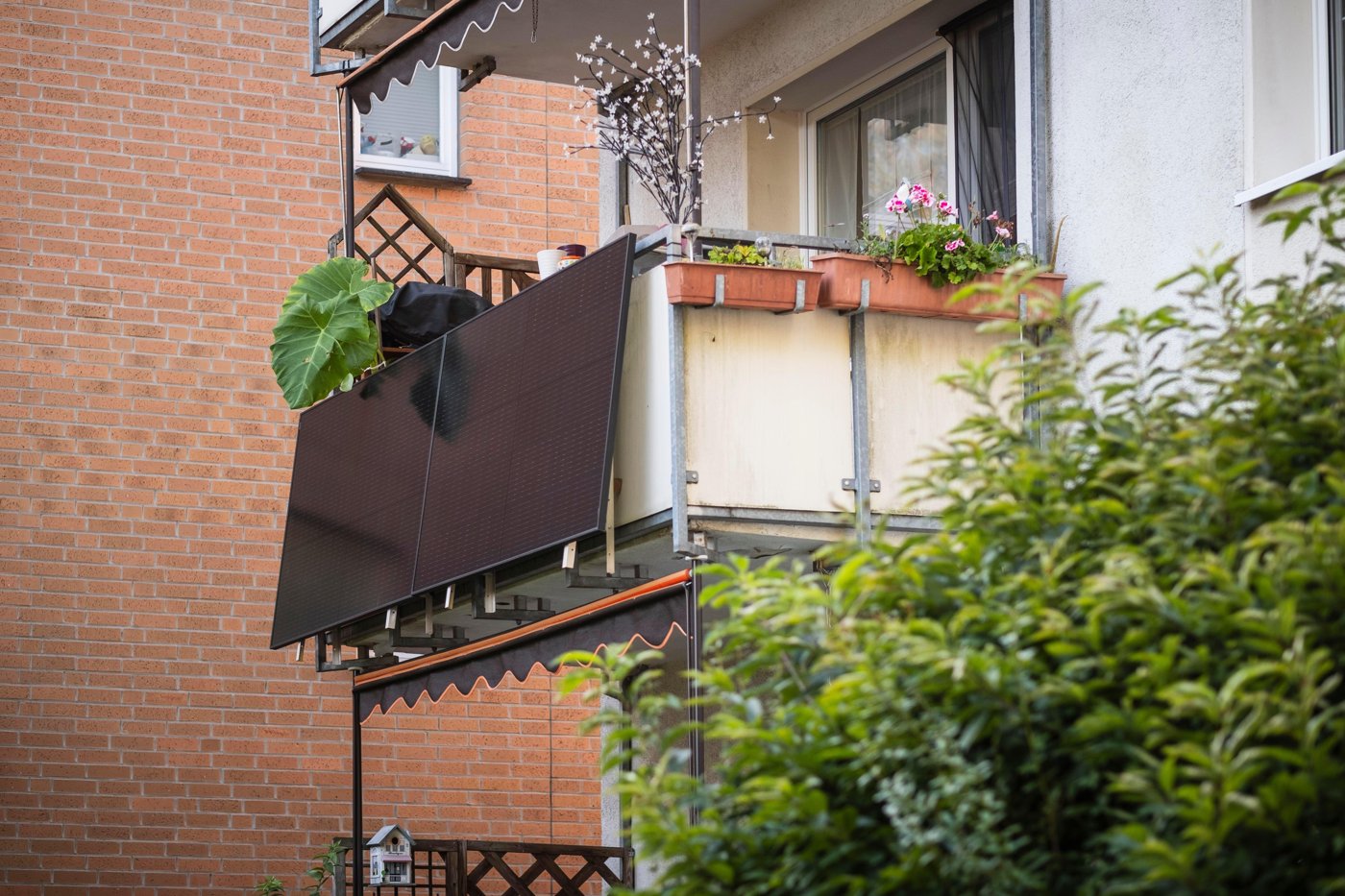 A balcony solar panel tilted out from a railing on an apartment building