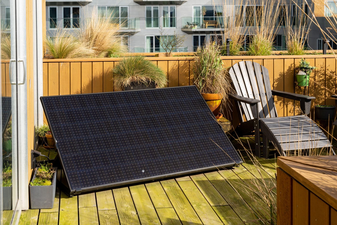 A freestanding solar panel leaning against a railing on a rooftop deck
