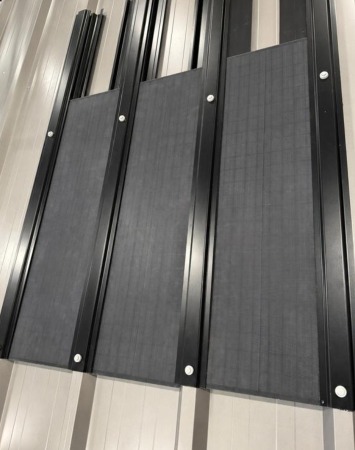 Completed vertical solar cladding array, collectors suspended between rails in uniform matte black
